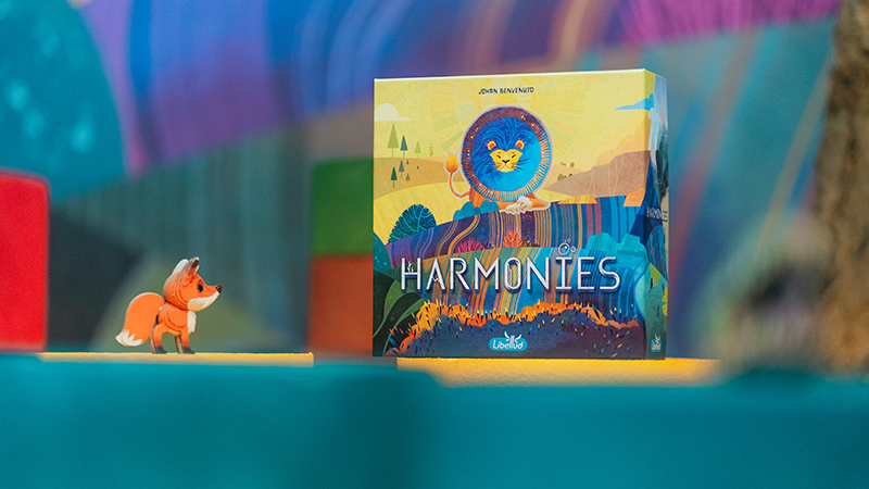 Boîte du jeu Harmonies de Libellud présentée avec son matériel et une figurine de renard
